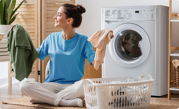 Indesit EcoTime IWSC 6105 — женщина достаёт чистое бельё из стиральной машины в домашних условиях
